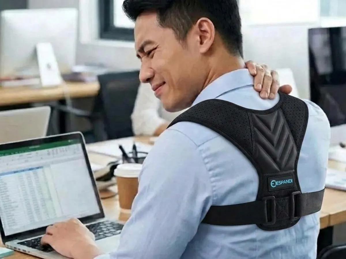 上班族男生在辦公室用筆電，穿著肩背支撐背心的 AI 情境示意